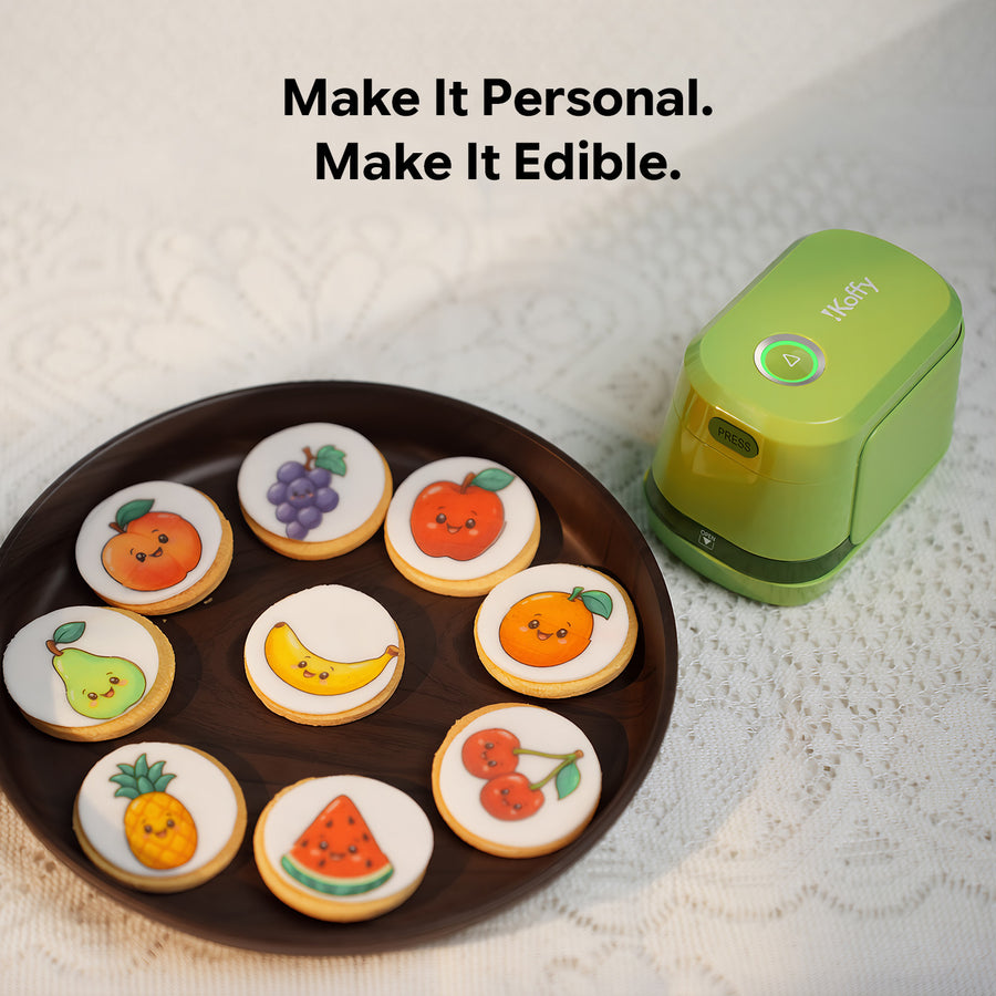 Green iKoffy EdiBot food printer beside iced cookies decorated with colorful fruit designs.